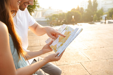 Loving couple walking outdoors while holding map.
