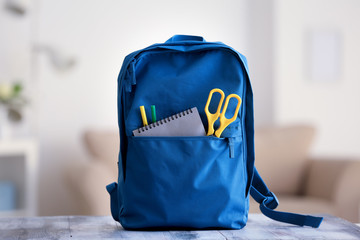 Backpack with school supplies on table