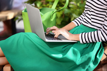 Beautiful young woman using laptop outdoors