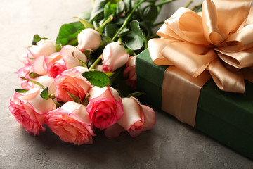 Beautiful roses with gift box on grey table