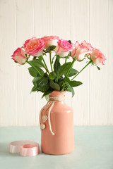 Vase with beautiful roses on light table