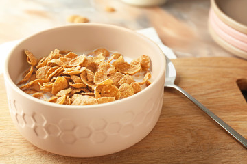 Bowl with healthy cornflakes and milk on board, closeup