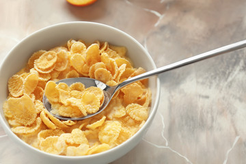 Bowl with healthy cornflakes and milk on color table