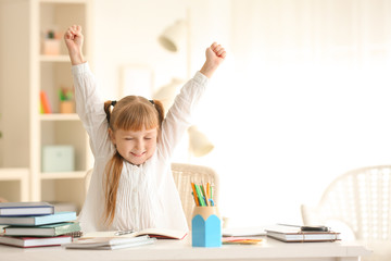 Happy little schoolgirl after finishing her homework