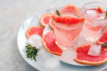 Fresh grapefruit cocktail with rosemary in glasses on plates