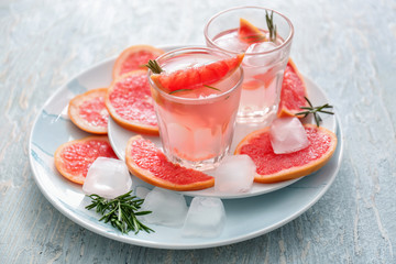 Fresh grapefruit cocktail with rosemary in glasses on plates
