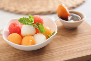 Plate with tasty melon dessert on wooden board