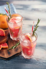 Fresh grapefruit cocktail with rosemary in glasses on wooden table