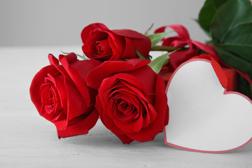 Beautiful red roses and blank card on light table