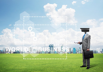 Camera headed man standing on green grass against modern cityscape