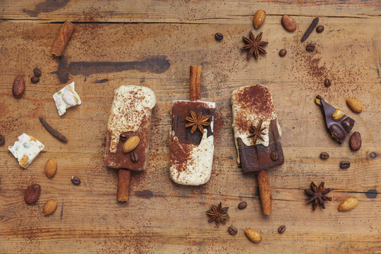 Homemade espresso and white chocolate ice lollies with winter spices on wooden background