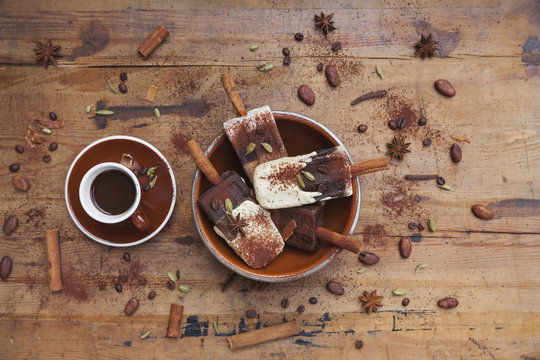 Homemade espresso and white chocolate ice lollies with winter spices and cup of espresso on wooden background