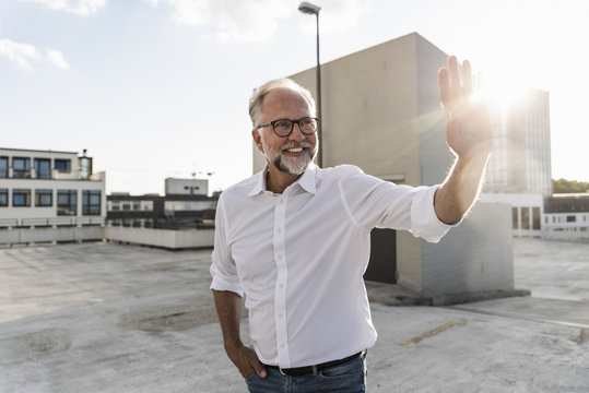 Mature man standing on roof of a high-rise building, catching the sun