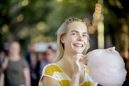 Portrait of happy young woman with candy floss on street food festival