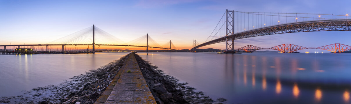UK, Scotland, Fife, Edinburgh, Firth of Forth estuary, Panorama view from South Queensferry of Forth Bridge, Forth Road Bridge and Queensferry Crossing Bridge at sunset