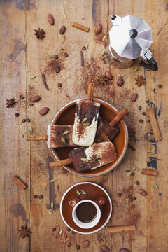 Homemade espresso and white chocolate ice lollies with winter spices, cup of espresso and espresso maker on wooden background