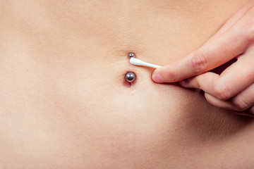 female navel piercing close-up with a cotton swab