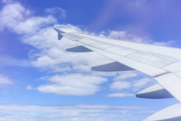 Scenery from airplane 's window viewing wing of airplane , white clouds and blue sky