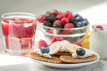 Waffles with cheese, yogurt and raspberries. A delicious wholesome breakfast on a light background. Very soft selective focus.
