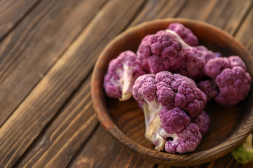 Bowl with purple cauliflower on wooden table