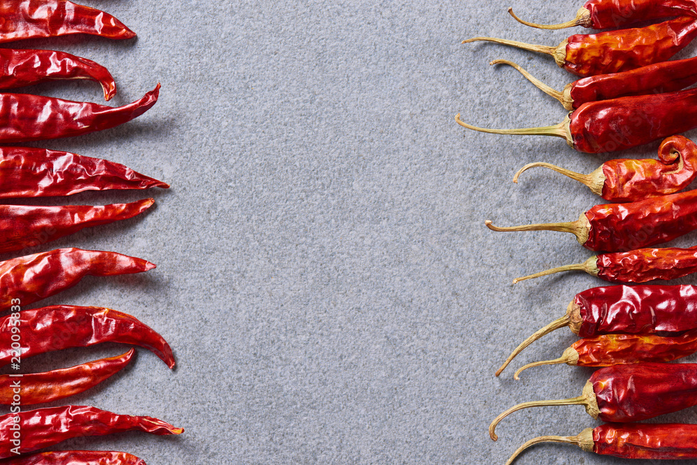 Wall mural top view of red chili peppers arranged on grey tabletop