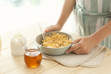 Obraz na płótnie Canvas Woman holding bowl with corn flakes at table