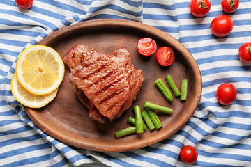Tasty grilled steaks with vegetables and sliced lemon on plate