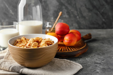 Tasty corn flakes in bowl on grey table