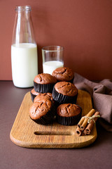 Homemade chocolate muffins (brownies) with cinnamon and milk on brown paper background