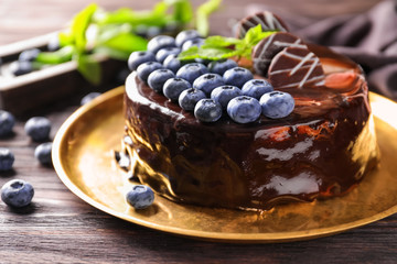 Metal tray with blueberry chocolate cake on wooden table