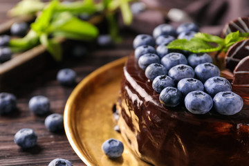Metal tray with blueberry chocolate cake on wooden table, closeup