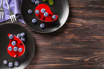 Plates with delicious blueberry desserts on wooden table