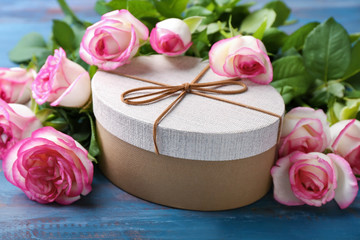 Beautiful roses and gift box on wooden table