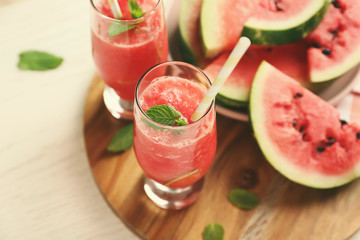 Glasses with fresh smoothie and watermelon slices on wooden board