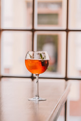 Aperol Spritz in wine glass on wooden table at the restaurant. Minimalism concept, food photography . Sun light, copyspace, vertical