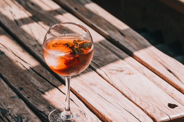 Aperol Spritz in wine glass on wooden table at the restaurant. Food photography. Direct sunlight, copyspace