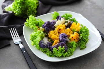Plate with colorful cauliflower on grey table