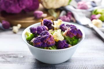 Bowl with colorful cauliflowers on wooden table