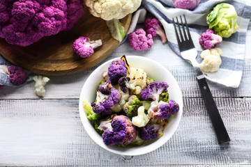 Bowl with colorful cauliflowers on wooden table