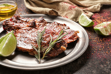 Metal plate with delicious grilled steaks on dark table