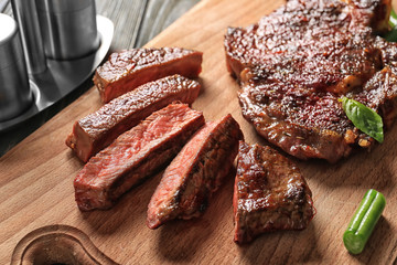 Delicious grilled steaks on wooden board, closeup