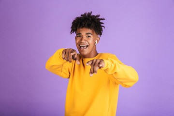 Portrait of young african american boy wearing bluetooth earbud smiling and gesturing index finger...