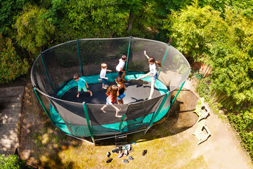 Boys and girls jumping on trampoline in the garden