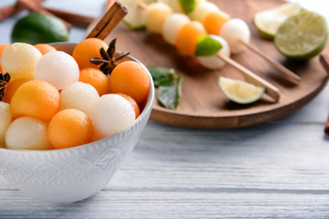 Bowl with delicious melon balls on wooden table, closeup