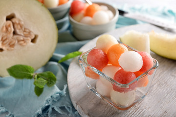Bowl with delicious melon balls on board