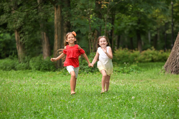 Naklejka na ściany i meble Cute little girls running in park on summer day