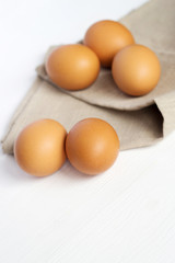 Brown chicken eggs on burlap on a white background