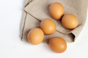 Brown chicken eggs on burlap on a white background