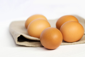 Brown chicken eggs on burlap on a white background