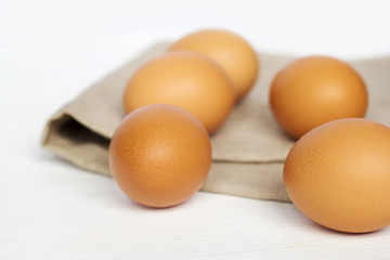 Brown chicken eggs on burlap on a white background